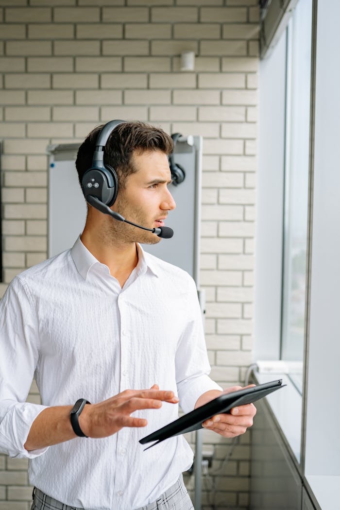 A young man with a headset and tablet in an office setting.